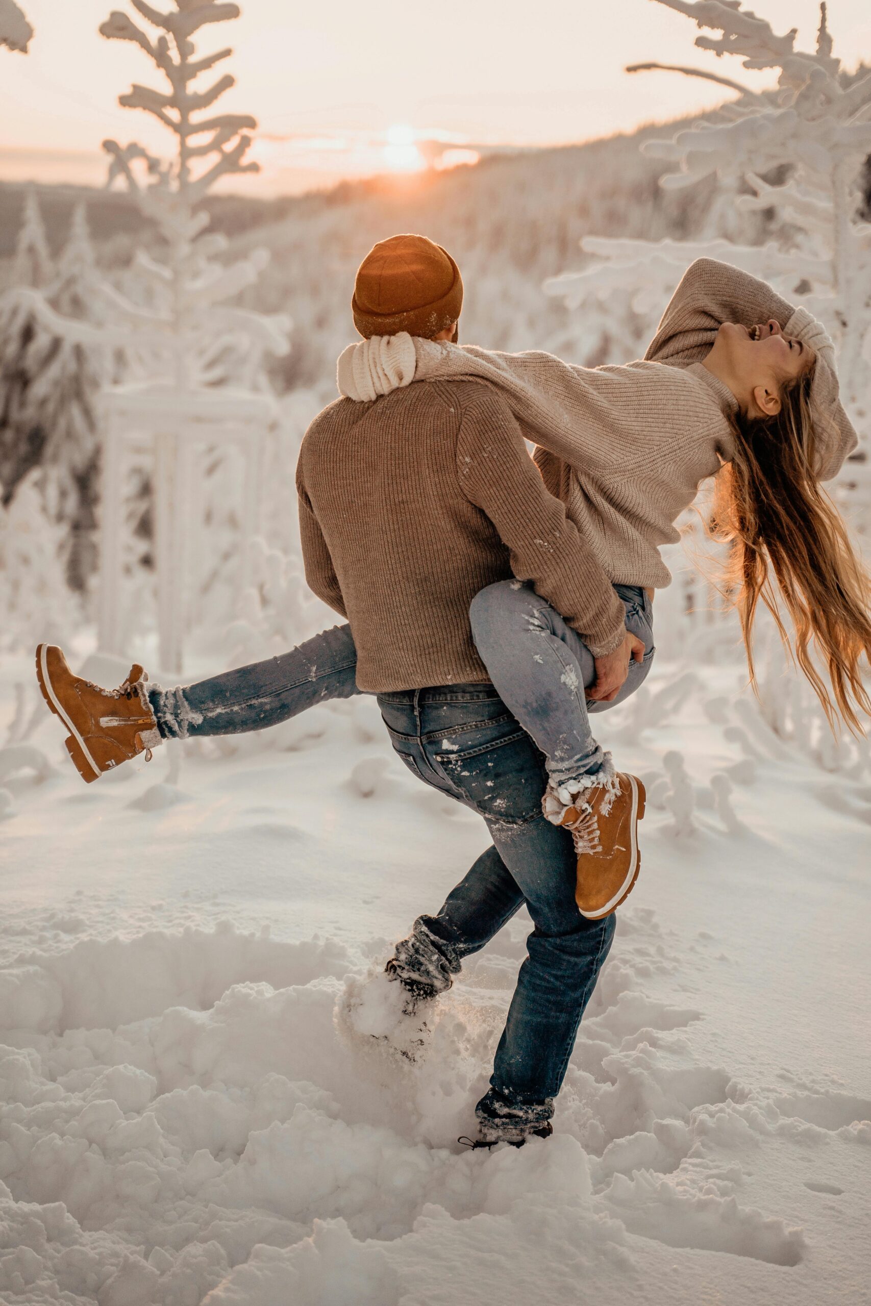 A couple playing in the snow at sunset, a moment during a winter-themed date. 