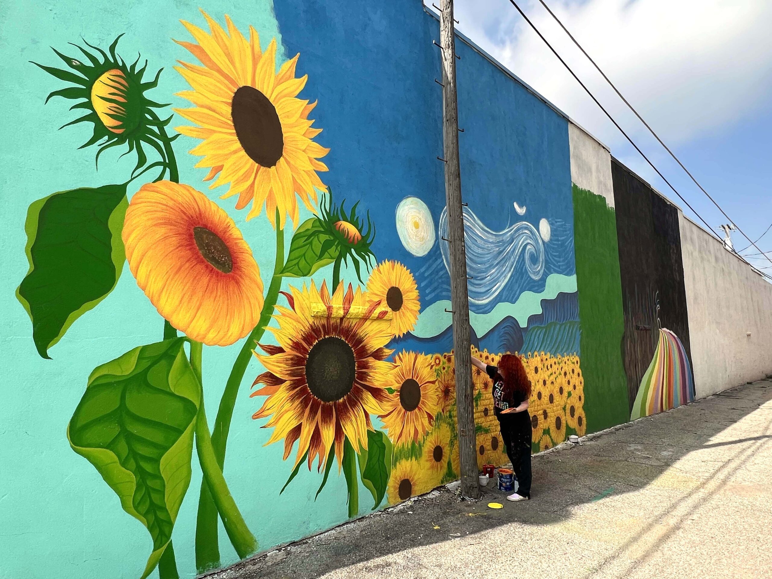 Local Ursula Goff explained that the concept for each mural panel evolved from organic conversations with locals and brainstorming ideas using an AI app. The sunflowers are a nod to the state's official flower.