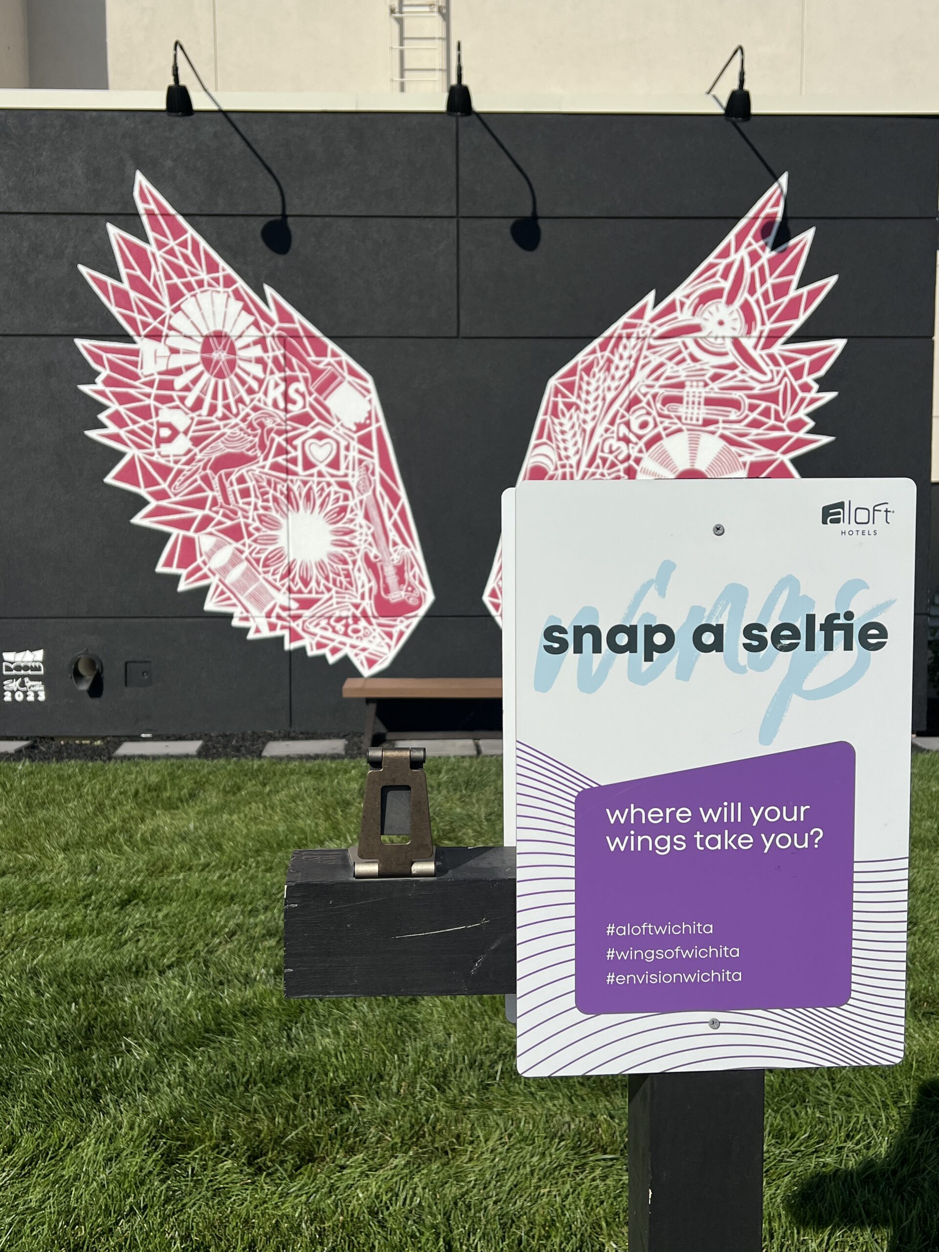 Envision Arts Selfie Station, situated near the Aloft Wichita hotel's guest parking, invites visitors to explore an interactive art experience.