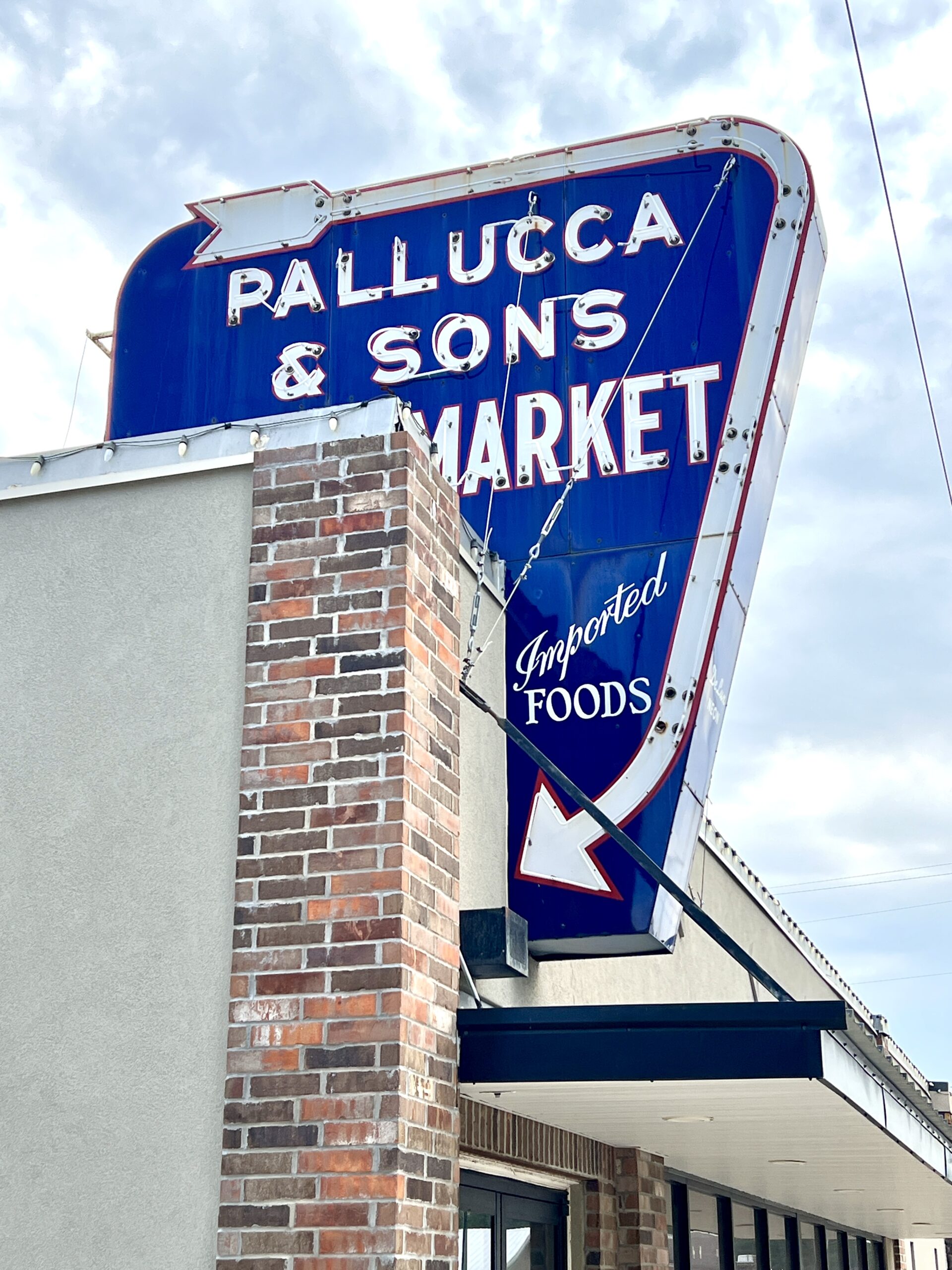 A vintage neon sign sits above Pallucas Italian Meat Market & Deli