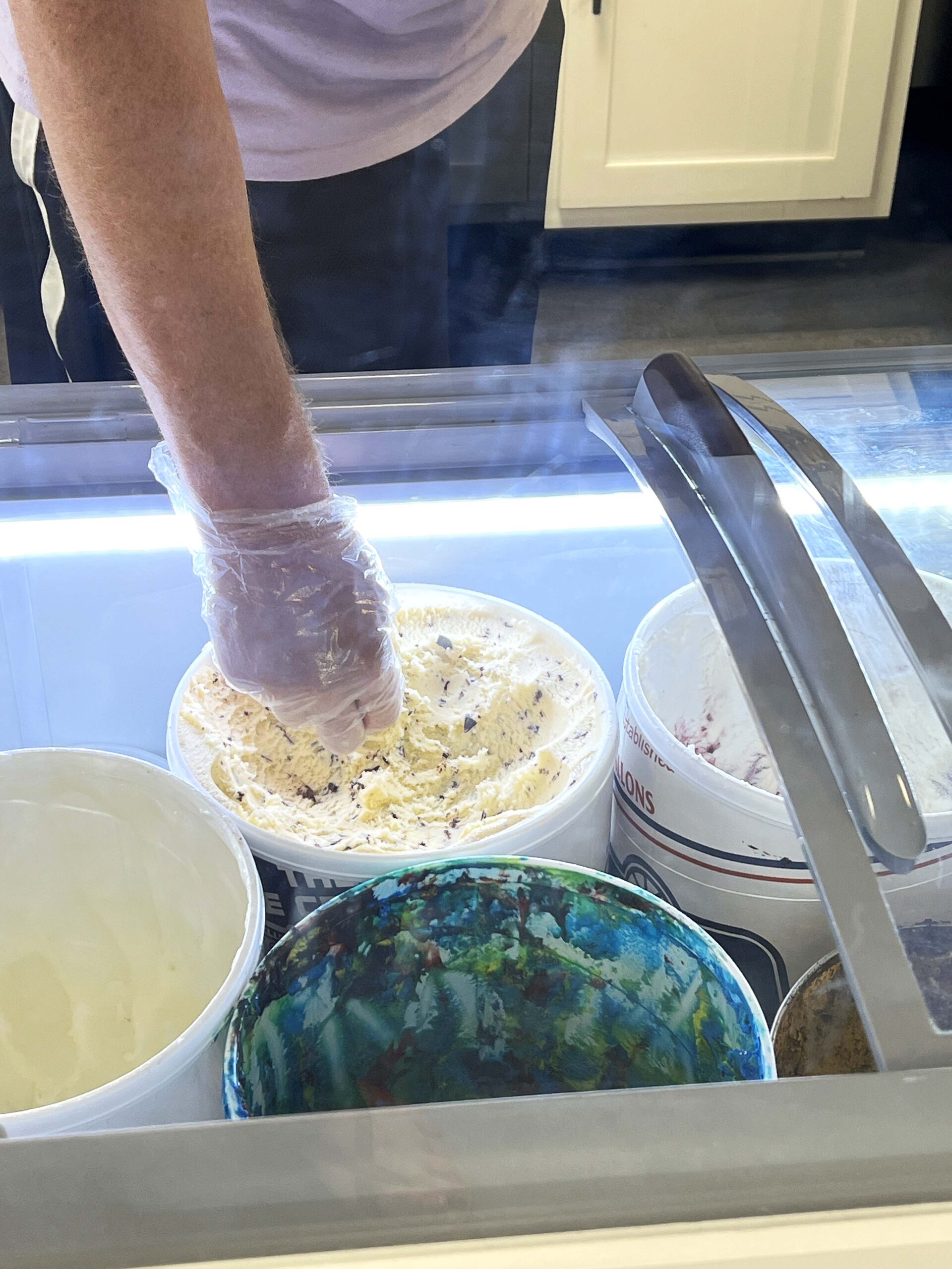An employee scoops a sample of a premium ice cream flavor. 