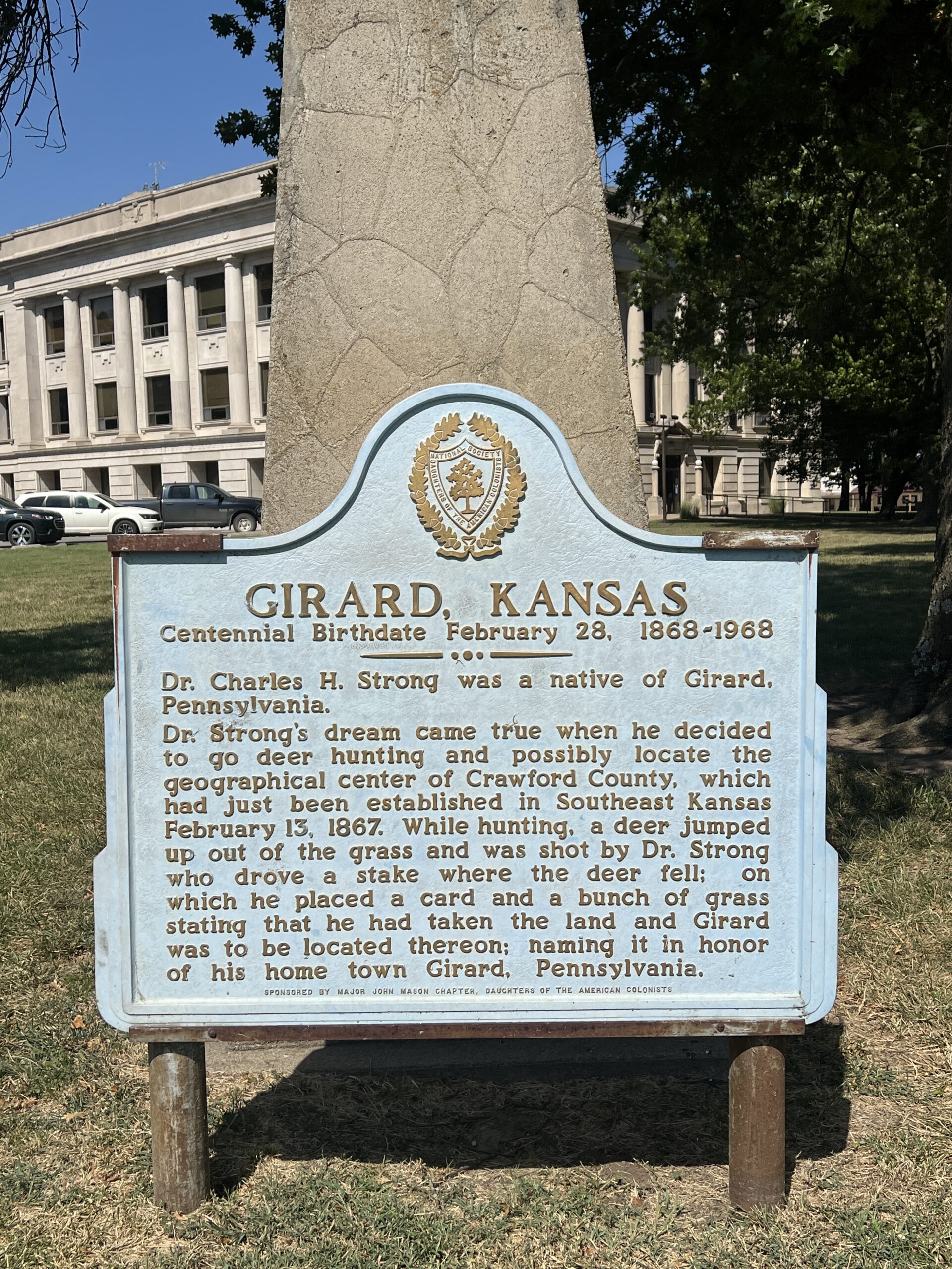 A historical marker beneath a deer sculpture tells the story of the town's founding.