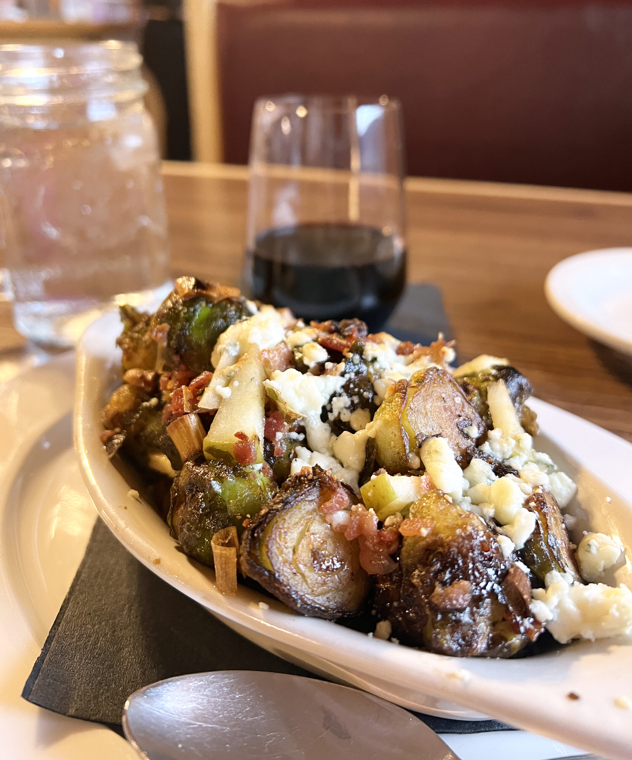 Roasted Brussels sprouts topped with cheese, bacon, and a dressing serve as an autumnal appetizer. 